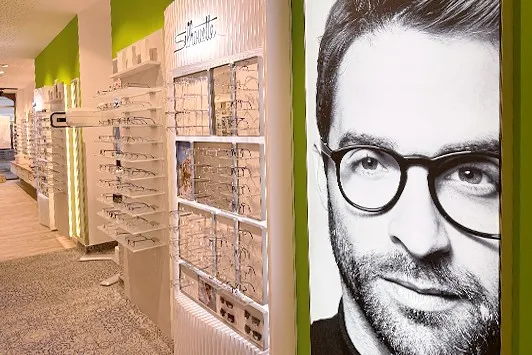 Optikgeschäft mit Brillenregalen und großem Porträt eines Mannes mit Brille