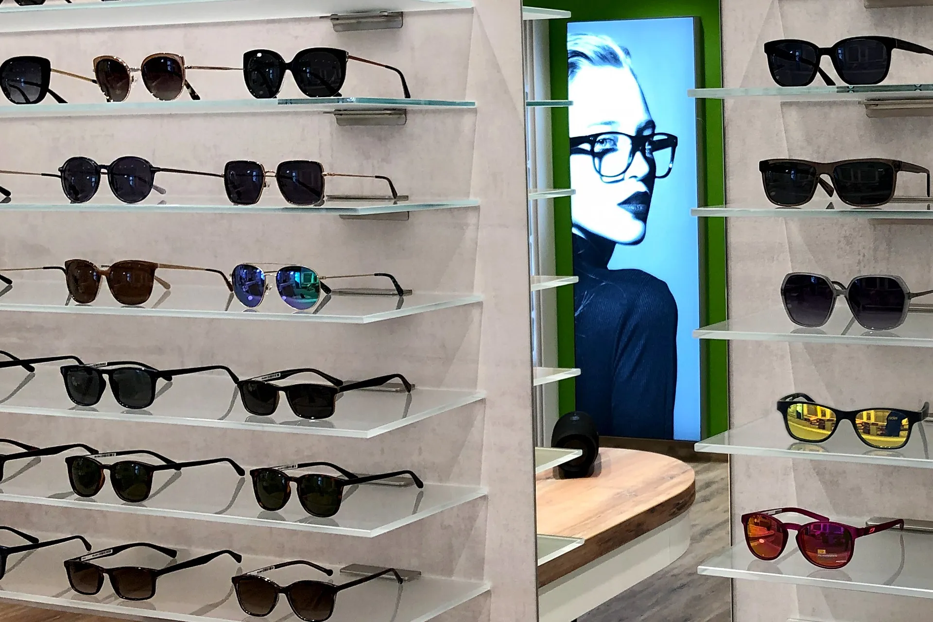 Sonnenbrillen und Brillenfassungen im Optikerladen auf Wandregalen, Posterfrau.